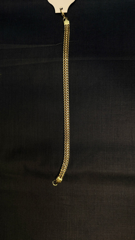 A gold-toned chain link accessory, likely a strap or chain detail, hanging vertically against a dark black textured fabric background.