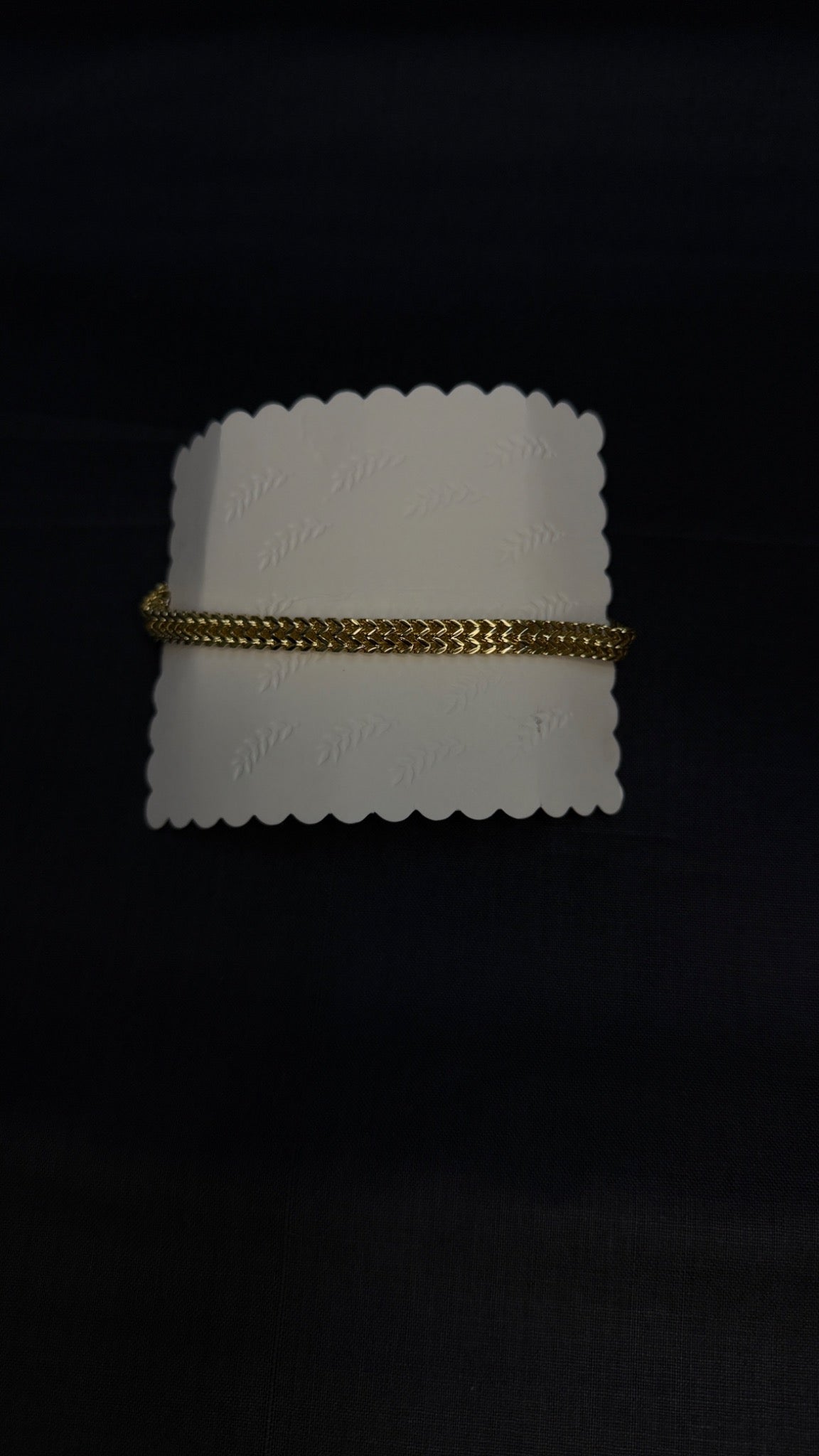 Gold bracelet on white display card
